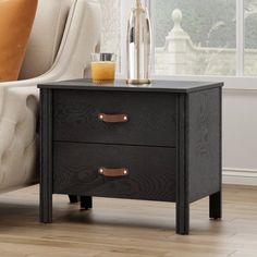 a black night stand with two drawers in front of a couch