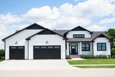 a large white house with black garage doors and windows on the front door is shown