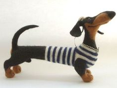 a toy dachshund wearing a striped shirt and beaded collar, standing on its hind legs