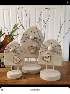 three wooden rabbits with hearts on their ears, one is holding a heart and the other has