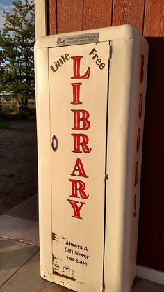 an old white library box sitting on the side of a building