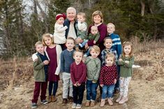 a large group of children and adults posing for a photo in front of some trees