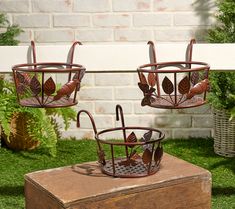 two metal planters sitting on top of a wooden box next to a brick wall