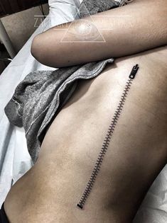 a person laying on a bed with a tattoo on their stomach and the end of his arm