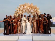 a group of people standing next to each other in front of an arch with flowers on it