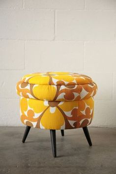 an orange and white ottoman sitting on top of a cement floor next to a brick wall