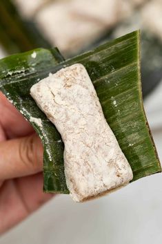 a person holding up a piece of food on top of a leaf