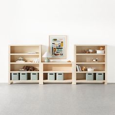 three bookshelves with baskets in front of them and a painting on the wall