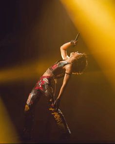 a woman is performing on stage with her hands in the air