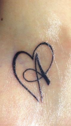 a small heart tattoo on the side of a woman's neck with an arrow in it