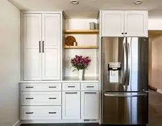 a kitchen with white cabinets and stainless steel refrigerator freezer combo in the center, along with black tile flooring