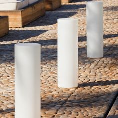 three tall white vases sitting on top of a stone walkway