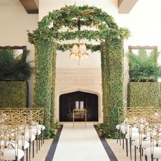 an indoor wedding ceremony setup with greenery and chandelier hanging from the ceiling