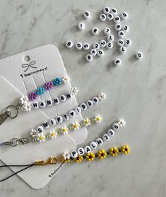 the beaded name key chain is on top of a white card with yellow and blue beads