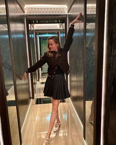 a woman is standing in an elevator and waving