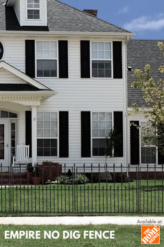 a large white house with black shutters and a clock on it's face