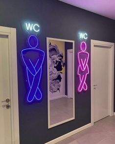 three neon signs are on the wall in front of two men's restrooms