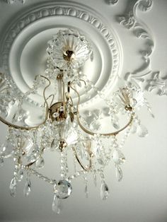 a chandelier hanging from the ceiling in a room with white walls and ceilings