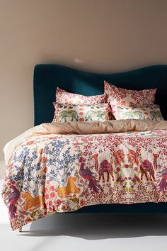 a bed with pillows and blankets on top of it in front of a white wall