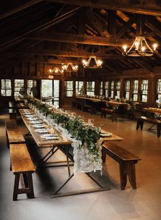 a long table is set up with place settings and greenery for an elegant wedding reception