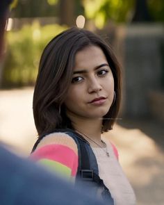 a young woman with shoulder bag looking at the camera while standing next to a man