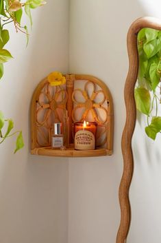 a wooden shelf with candles on it next to a potted plant in a corner