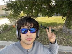 a man with headphones and sunglasses making the peace sign