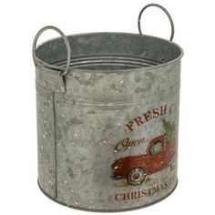 an old fashioned metal bucket with a christmas tree on the front and bottom, hanging from it's side