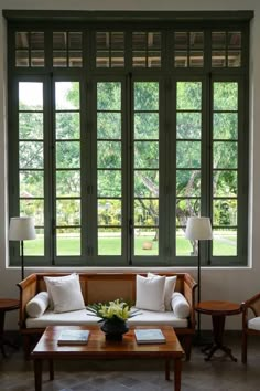 a living room filled with furniture next to large windows and lots of green shutters