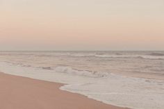 two people walking on the beach with surfboards