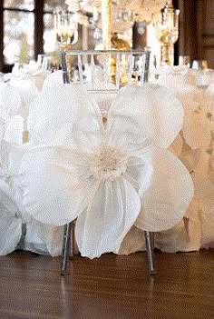 the table is covered with white ruffles and flowers