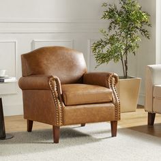 a brown leather chair sitting on top of a wooden floor next to a potted plant