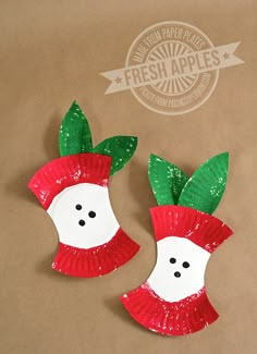 two plastic red and green christmas decorations on brown paper bag with white button in center