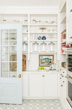 a kitchen with white cabinets and glass doors