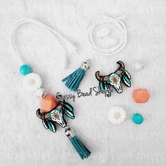 two cow brooches with tassels and beads are laying on a white blanket