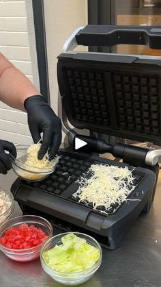 a person in black gloves is making food on a waffle iron