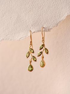 P E R I D O T∙ E A R R I N G S These earrings are crafted with 24k gold vermeil over 925 sterling silver. Each earring features an elegant leaf design, adorned with pear and marquise-cut peridot gemstones that evoke the freshness of nature. The vibrant green hues of the peridots create a stunning contrast against the warm gold, adding a touch of sophistication to any outfit. This earring is also available in Garnet, Blue Topaz, Amethyst, Citrine and Iolite Gemstones. Please write to us for customisations.  * Material:  24K Gold Vermeil on 925 Sterling Silver - Hypo-Allergenic and Nickel Free * Finish: 24K Gold Vermeil on 925 Sterling Silver | Also available in solid 925 Sterling Silver * Featuring 6 Pieces of 3*6 MM Marquise and 2 Pieces of 5*7 Pears Peridot natural gemstone. * Total Stone Pretty Earrings Dangle, Handcrafted Silver Jewelry, Peridot Jewelry, Peridot Earrings, Natural Jewelry, August Birthstone, Green Hues, Natural Stone Jewelry, Peridot Gemstone