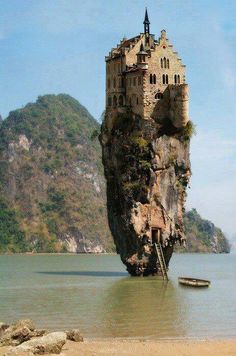 an island with a castle built on it in the middle of water next to a mountain