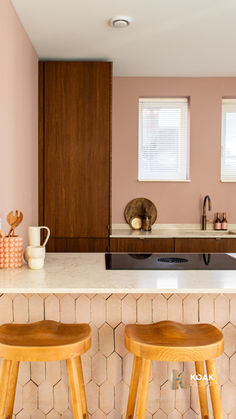 two wooden stools sitting in front of a kitchen counter