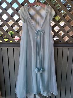 A beautiful pale blue chiffon and nylon peignoir robe by Lucie Ann Beverly Hills. Has a gorgeous wide sweep and classic pompom ties. It is in good condition, with some surface issues. There is light yellow discoloration on the sleeves. You can see the shade difference in the last photo, where I compare the sleeves to the hem. There are some small tears/holes in the chiffon one at the top near the bust, and 3 near the hem, and a yellow stain in the front. There are picks in the nylon and chiffon, and the nylon hem is 2 or 3 inches longer than the chiffon layer (see 2nd to last photo). Bust - at least 32" (81 cm)  Waist - at least 36" (91 cm)  Hips - Open Length - 50" (127 cm) Sleeves - 4" (10 cm) Arm holes - 14" (35 cm) in circumference I estimate this to fit a size Small to a Medium. Blue Nightgown, Costume Clothes, Hip Openers, Pajama Robe, Womens Robes, Costume Outfits, Light Yellow, Pale Blue, Beverly Hills