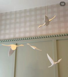 some paper birds are hanging from the ceiling in front of two mirrors and one bird is flying