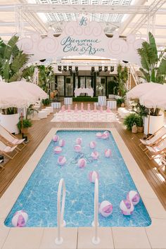 an indoor swimming pool with chairs and umbrellas in the middle, surrounded by palm trees