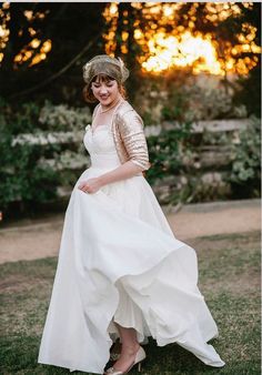 a woman in a white dress and hat posing for a photo with trees in the background