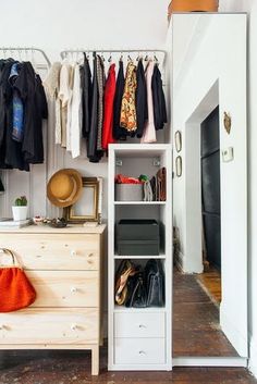 an organized closet with clothes and handbags hanging on the rack, next to a dresser