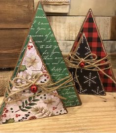 three small christmas trees are sitting on a table with twine and burlocks