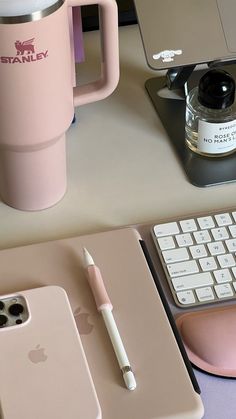 an iphone, keyboard, and cup sitting on top of a desk next to a computer