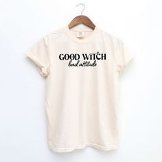 Looking for a cute versatile top to wear this summer? Make sure to grab one of our Good Witch Bad Attitude garment dyed graphic tees! This soft and comfortable graphic tee is the perfect top for any outfit. It can be paired with biker shorts, jeans, or even a simple skirt/dress! This tee is true-to-size, so be sure to order your regular t-shirt size! If you are looking for a more oversized look, make sure to size up! Acid Wash Cotton Slogan Top, Acid Wash Cotton Top With Slogan, Summer Organic Cotton Washed Tops, Acid Wash Cotton T-shirt With Slogan, White Washed Graphic Tee, Summer Slogan T-shirt In Organic Cotton, Organic Cotton Summer T-shirt With Slogan, Summer Organic Cotton Tops With Slogan, White Washed T-shirt For Summer