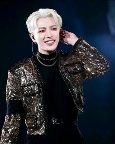 the young man is smiling while wearing a black shirt and gold sequinned jacket