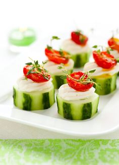 small cucumber cakes with strawberries and whipped cream on top are arranged on a white platter