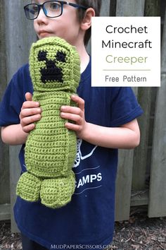 a young boy holding a green crocheted stuffed animal